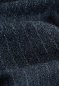 Donkerblauwe wollen stof met een zachte, fuzzy textuur en subtiele lichtere strepen, die een rijke, gedempte kleurnuance laat zien.