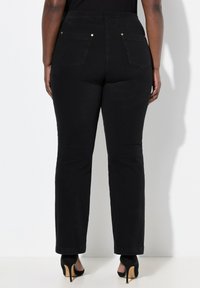 Jeans de mezclilla negra con un diseño de pierna recta, que cuentan con bolsillos traseros y acentos en tono dorado. Terminados con una textura suave.