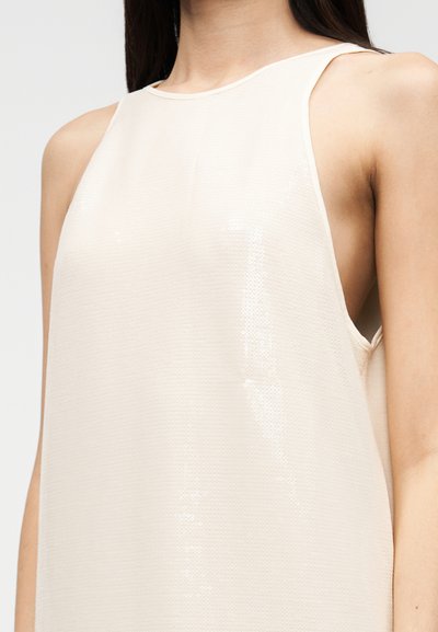 Μπεζ αμάνικο τοπ με υφή και ελαφρώς γυαλιστερό φινίρισμα, με στρογγυλή λαιμόκοψη και κοψίματα στους ώμους.