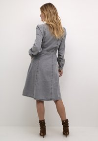 Gray denim dress with long sleeves, fitted waist, and below-knee length. Features visible stitching and a tied belt at the waist.