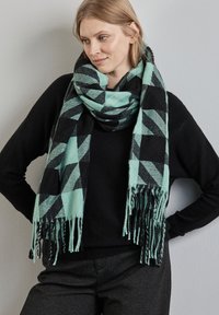Bufanda de cuadros en verde menta y negro, con una textura suave y bordes con flecos, envuelta alrededor del cuello sobre un fondo neutro.