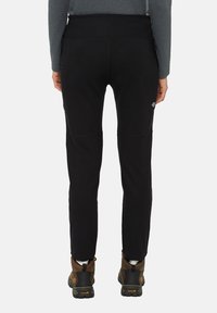 Zwarte sportieve broek met een aansluitend ontwerp, voorzien van textuurstof, platte naden en kniestukken. Draag met bruine wandelschoenen.