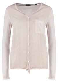 Chemise beige clair à manches longues avec boutons, col en V, poche poitrine à gauche et un détail noué sur l'ourlet inférieur.