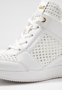 Sneaker high-top in pelle bianca con pannelli in rete intrecciata, suola in gomma spessa e dettagli in hardware argentato con branding.