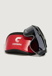 Occhiali da sole Carrera neri con design elegante, lenti grigie e dettagli perforati, riposti in un astuccio rigido rosso con logo bianco.