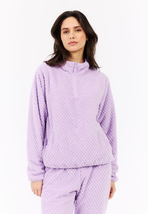 Pull en polaire lilas avec un design à demi-zip, présentant une surface texturée et un col montant. Le tissu semble doux et confortable.