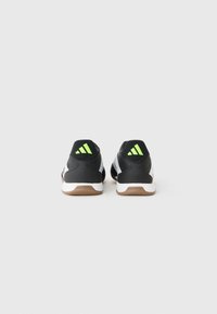 Black athletic shoes with white accents, featuring a textured back, green details, and a brown rubber outsole. Three stripes logo visible.