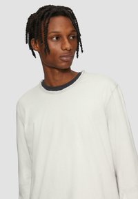 Witte blouse met lange mouwen en een ronde halslijn, voorzien van een contrasterende donkere binnenkraag en een relaxte pasvorm, gemaakt van zachte, gestructureerde stof.