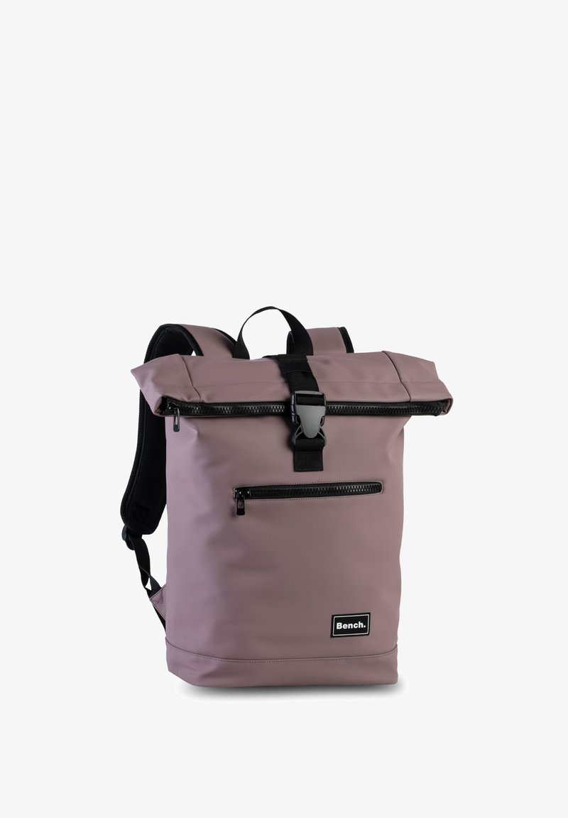 Lila Rolltop-Rucksack aus strapazierfähigem Material mit schwarzen Trägern. Verfügt über eine vordere Reißverschlusstasche und ein Logo-Patch am Boden.