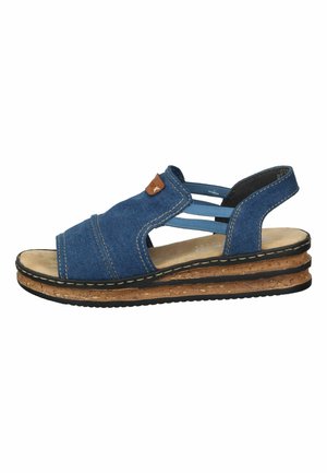 Sandale compensée en denim bleu avec une semelle en liège, des sangles élastiques et une étiquette d'accent marron. Le design est ouvert à l'avant et comporte une semelle intérieure rembourrée.