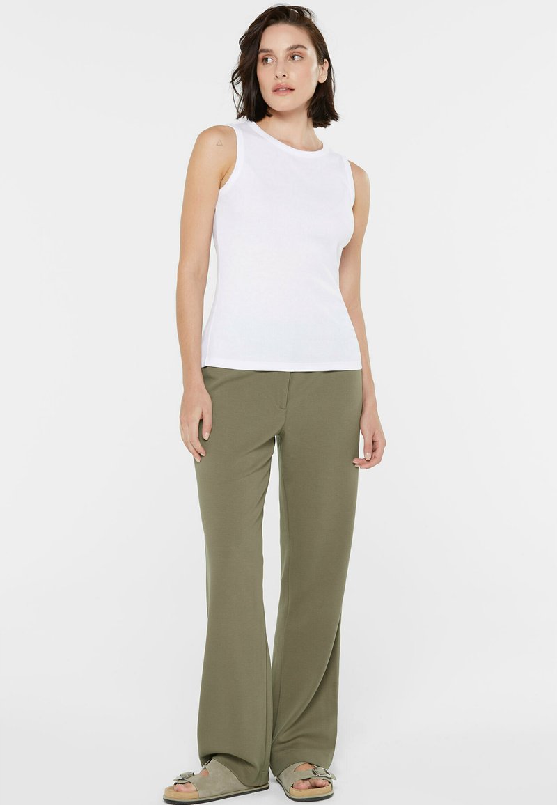 White sleeveless top with a round neckline paired with olive green wide-leg pants. The top has a ribbed texture, and the pants are smooth.