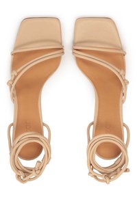 Beiga fyrkantiga sandaletter med en slät läderovandel, tunna remmar som lindar sig runt vristen och en platt sula. Minimalistisk design.