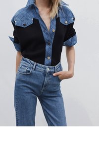 Svart och jeansskjorta med korta ärmar, med en kviltad blå krage och framknäppning med guldknappar, tillsammans med ljusblå jeans.