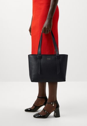 Navy textured leather tote bag with dual top handles, featuring a minimalistic design and a small logo detail on the front.