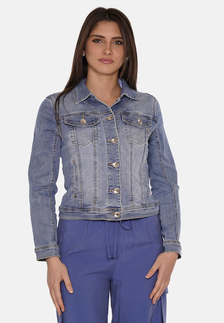 Giacca di jeans in blu chiaro, design corto con bottoni metallici, tasche frontali e texture sbiadita. Indossata sopra pantaloni blu scuro.