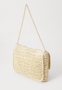 Bolso de mano rectangular tejido en color beige con un patrón texturizado y una delgada correa de cadena dorada para el hombro, sobre un fondo blanco.