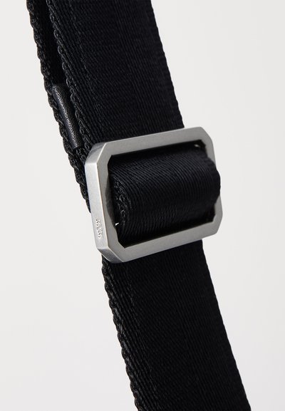 Cintura in nylon nero con una elegante fibbia in metallo argentato di forma ottagonale, che mette in evidenza una superficie liscia e un design resistente.