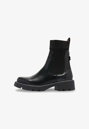 Bottine noire en cuir et textile élastique. Dotée d'un motif croco texturé, d'une semelle épaisse et d'un accent métallique décoratif.