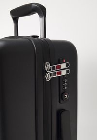 Black hard-shell suitcase featuring a retractable handle, double zipper locks with a red and silver design, and dial combination lock on the side.