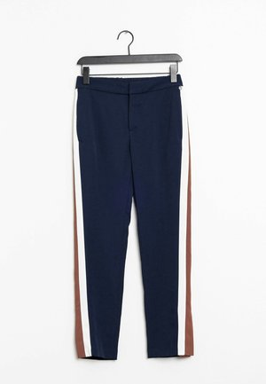 Pantalon bleu marine avec des bandes verticales blanches et marron sur les côtés, suspendu à un cintre noir sur fond blanc.