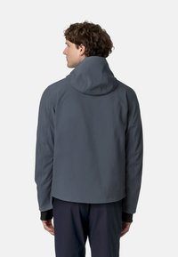 Szara wodoodporna kurtka z dopasowaną kapturem, elastycznymi mankietami i widocznymi detalami szwów. Gładka faktura i dopasowany design z tyłu.