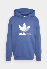 Blå adidas-hoodie i en mjuk bomullsblandning, med en framficka, justerbar snörhuva och en vit logotyp med tre ränder.