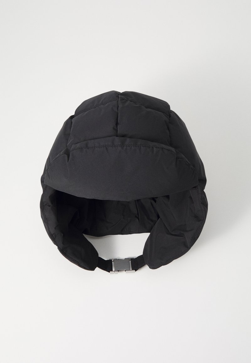 Black padded hat with a rounded shape, featuring a chin strap and smooth texture. The design includes stitch detailing for added structure.