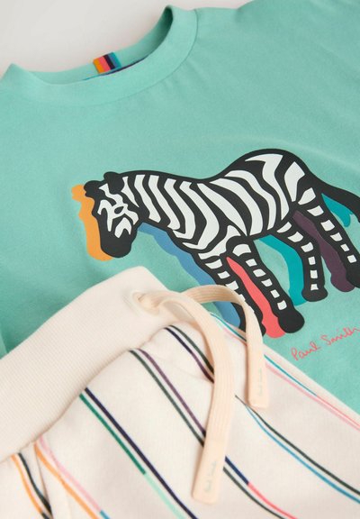 Lyseblågrøn skjorte med flerfarvet stribet zebra-grafik og cremehvide shorts med flerfarvede striber og beige snørebånd.