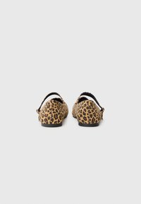 Sapatos planos com padrão de leopardo, apresentando um superior macio e texturizado, tira traseira e sola plana. Tem um fundo preto e um padrão de leopardo em castanho e preto.