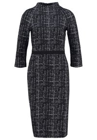 Svart och vit mönstrad klänning med hög krage, trekvartslånga ärmar och figurnära midja. Slät textur med en subtil vävdesign.