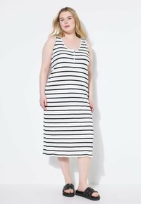 Gestreiftes Maxikleid in Schwarz und Weiß. Hat einen Rundhalsausschnitt, Knopfdetaillierung an der Brust und einen lockeren Schnitt. Kombiniert mit schwarzen Sandalen.