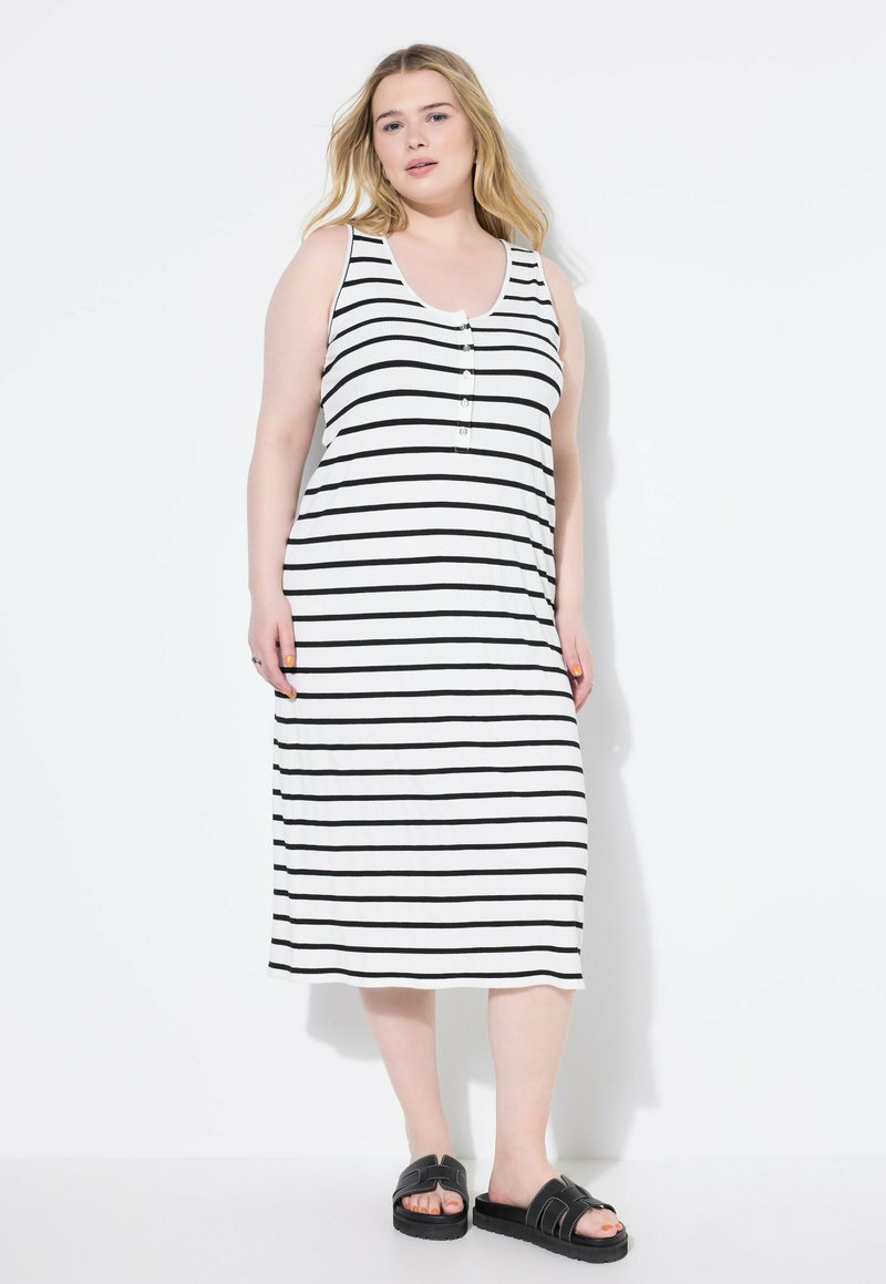 Gestreiftes Maxikleid in Schwarz und Weiß. Hat einen Rundhalsausschnitt, Knopfdetaillierung an der Brust und einen lockeren Schnitt. Kombiniert mit schwarzen Sandalen.