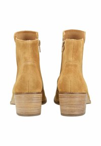 Botines de ante en color mostaza, con un tacón grueso apilado y cremallera lateral para facilitar su uso. Superficie texturizada con líneas limpias.