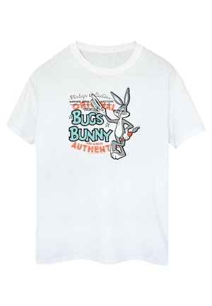 Fehér pamut póló, amelyen Bugs Bunny grafikai tervezése látható fekete, kék és narancssárga szöveggel. Rövid ujjú, kerek nyakkivágással.