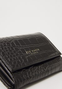 Black crocodile-embossed wallet with a shiny texture, featuring a gold logo and a fold-over design for secure closure.