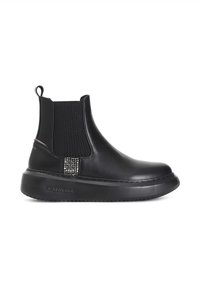 Botas negras de tobillo con suela de goma, paneles laterales elásticos y un acento metálico decorativo en el talón. Parte superior de cuero suave con un acabado texturizado.