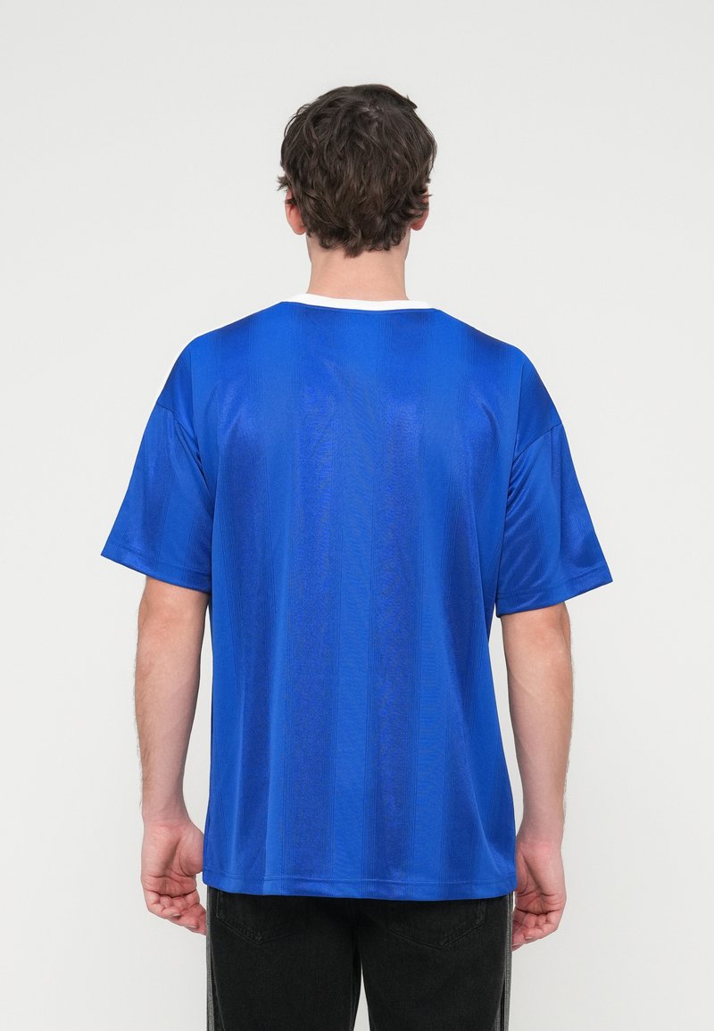 Blaues T-Shirt mit kurzen Ärmeln, einer strukturierten Oberfläche und einem kontrastierenden weißen Rundhalsausschnitt. Das Material wirkt leicht und atmungsaktiv.