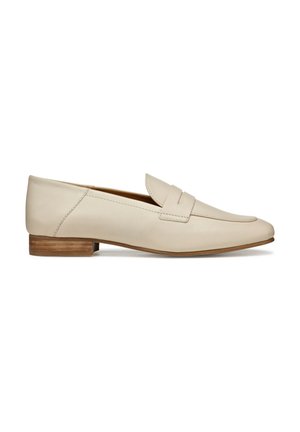 Mocassins en cuir beige avec un design à bout pointu, présentant un détail de sangle cousue et un petit talon en bois. Texture lisse sur l'ensemble.