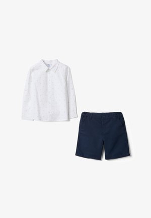 Camisa blanca de manga larga con botones, con pequeños patrones oscuros de anclas y pantalones cortos elásticos de cintura azul marino para niños.