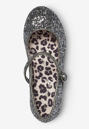 Zapato Mary Jane plateado brillante con plantilla de estampado de leopardo y correa con hebilla metálica, visto desde arriba sobre fondo blanco.