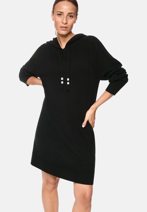 Schwarzes gestricktes Hoodie-Kleid mit langen Ärmeln, ausgestattet mit einem gerippten Saum und zwei weißen Akzentstreifen an den Kordeln. Weiche Textur.