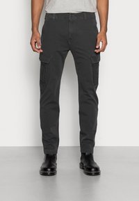 Mörkgrå cargobyxor med slim fit, med två sidofickor, slitstarkt tyg och rak bendesign. Bärs med svarta ankellång stövlar.