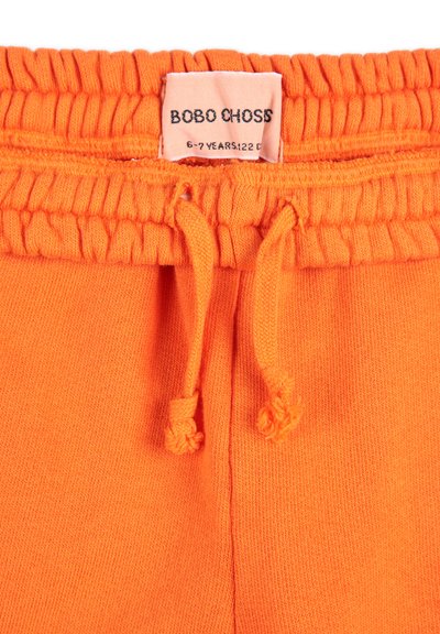 Orangene Sweatpants mit elastischem Bund, verstellbaren Kordeln und weichem Material. Das Etikett lautet "BOBO CHOSS, 6-7 JAHRE, 122."