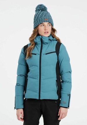 Tessellierte, gepolsterte Winterjacke in Petrol mit schwarzen Akzenten, hohem Kragen und Reißverschluss-Taschen. Komplett mit einer blauen Strickmütze mit Bommel.