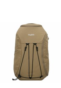 Sac à dos beige en tissu texturé, doté d'une fermeture éclair sur le dessus et de cordes bungee à l'avant pour un rangement supplémentaire. Logo affiché sur le devant.