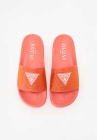 Korallfärgade slide-sandaler med en texturerad gummibas. Har en rem med klara strasstenar och vit logotyptriangel som detalj.