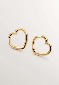 Pendientes de aro dorados en forma de corazón, con un acabado liso y brillante, y un diseño abierto con una bisagra para facilitar su uso.
