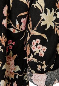 Μαύρο ύφασμα με floral μοτίβο σε απαλό ροζ, μπεζ και κρεμ, που δείχνει μεγάλα και μικρά λουλούδια με φύλλα και μίσχους.