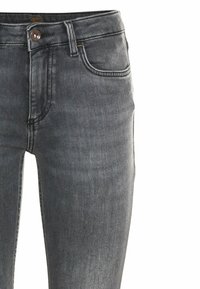 Jeans de denim gris con corte ajustado, con cierre de botón y cremallera, bolsillos delanteros y detalles de costura visibles. Textura suave.