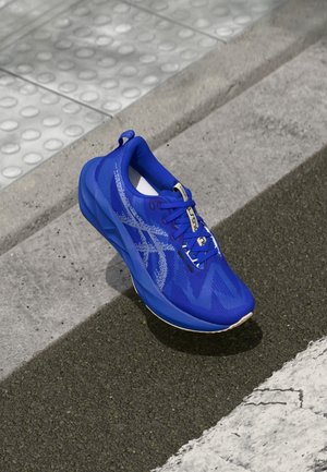 Blue athletic shoe with a textured mesh upper and unique graphic design. Features a padded collar, laces, and a rubber sole.